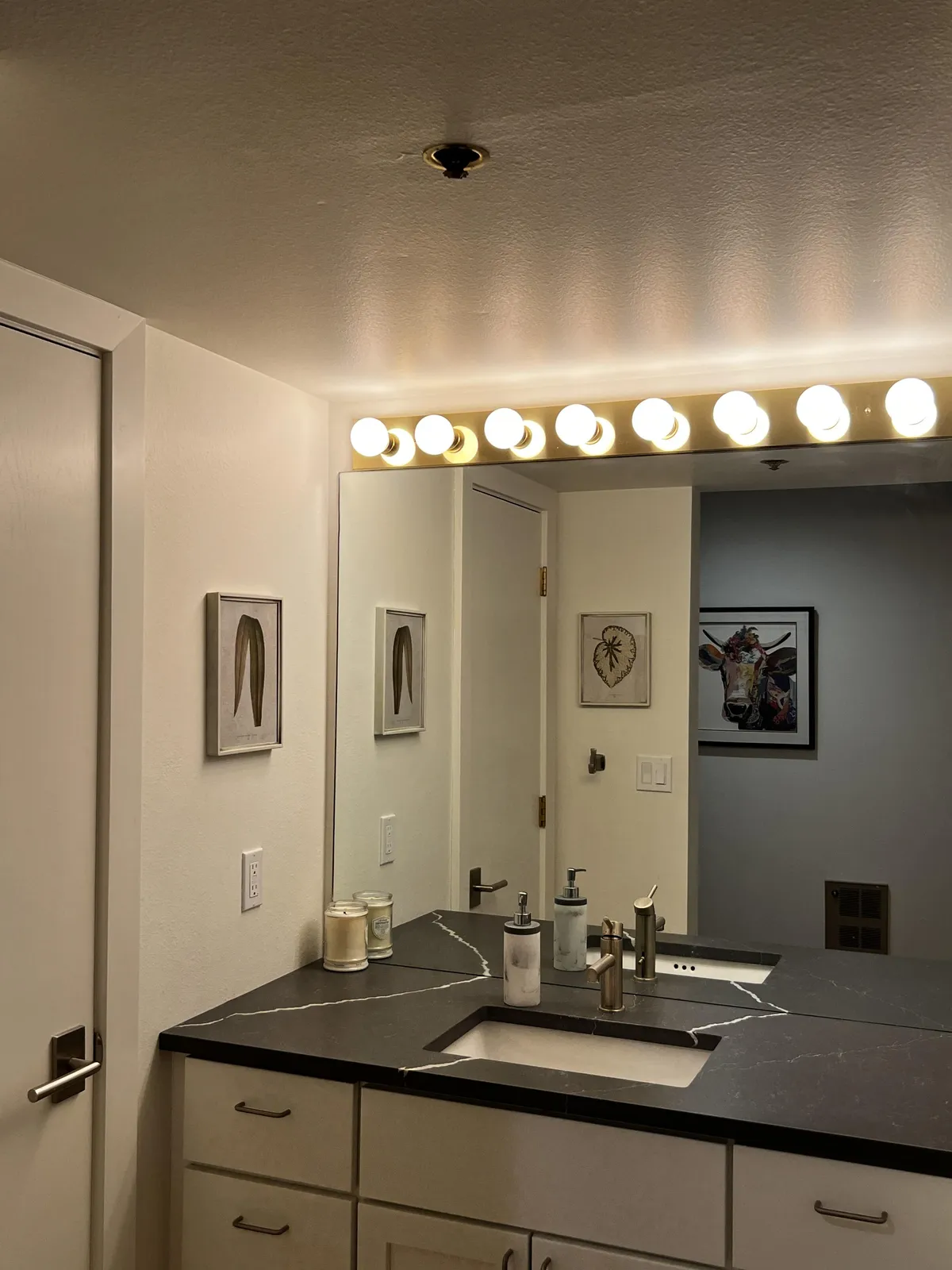 Here, a mirror with soft lighting, a modern sink area, and decorative artwork come together in a compact, serene bathroom nook. The lighting suggests a calm, relaxing mood ideal for self-care and winding down after adventure.